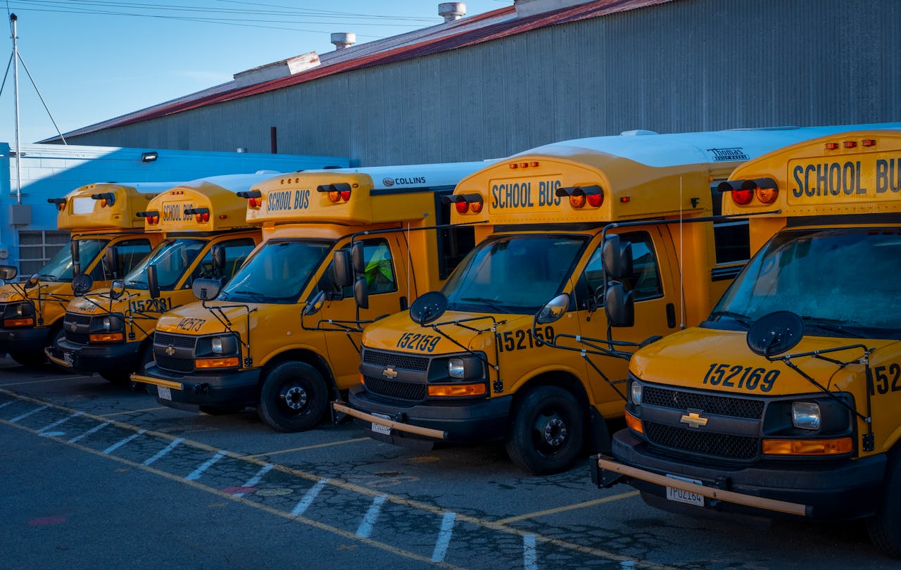 portfolio-04 A line of yellow school buses parked outside a building during the day.